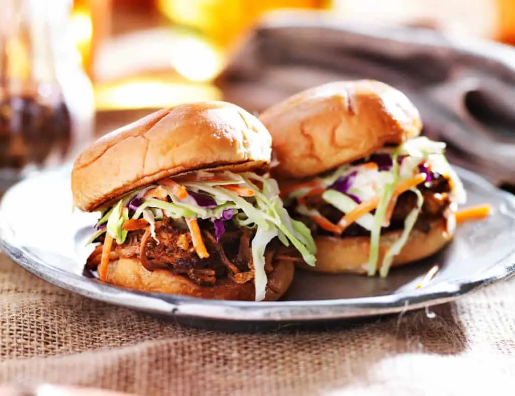 Pulled pork sandwiches with bbq sauce and slaw on a silver plate.