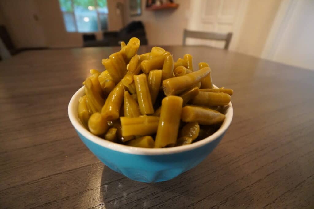An overflowing bowl of green beans on a table.