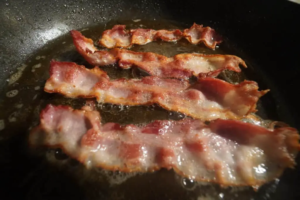 Sizzling bacon cooking in a pan.