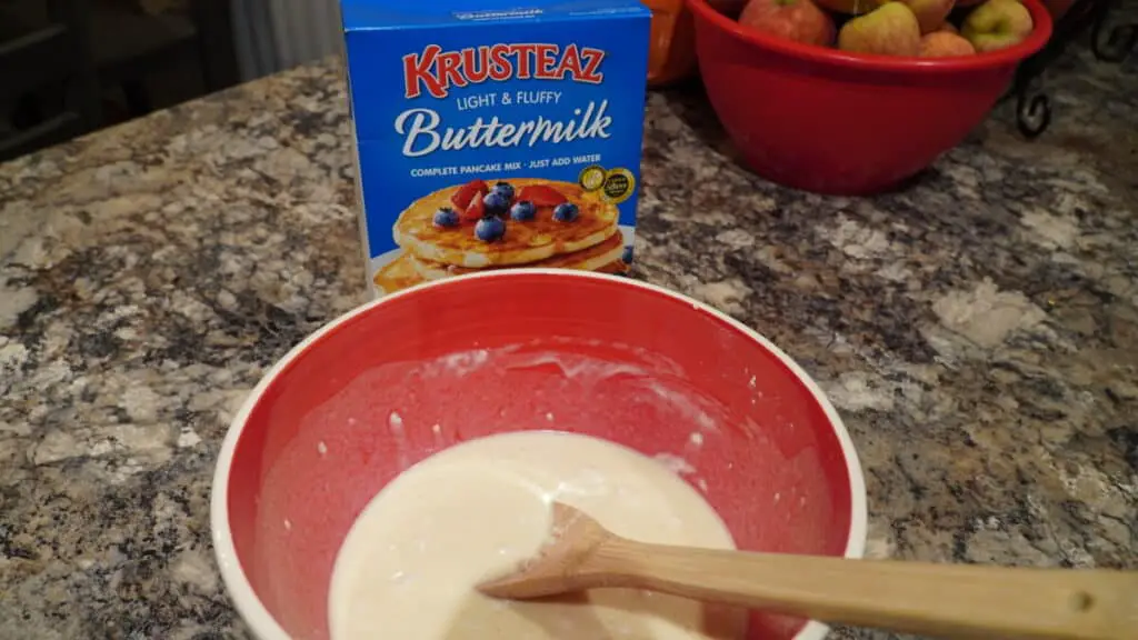 Pancake mix in red bowl with Krusteaz pancake box in background.