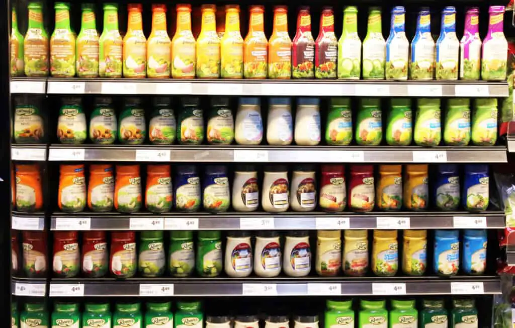 Variety of salad dressing bottles on shelves in a grocery store.