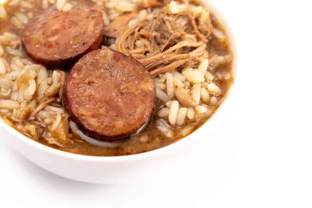 A bowl of sausage and chicken gumbo with rice,