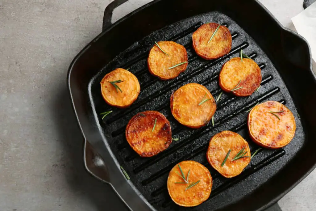 Grill pan with sweet potato fries on grey background, top view.
