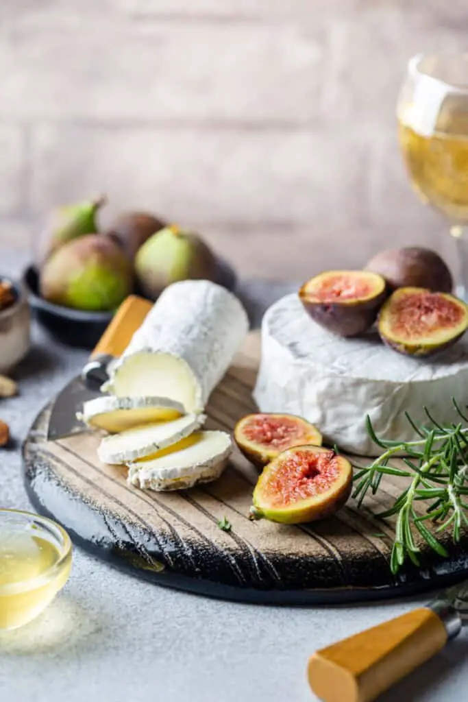 Fresh goat brie cheese with truffle and white mold on cheese platter with figs and honey