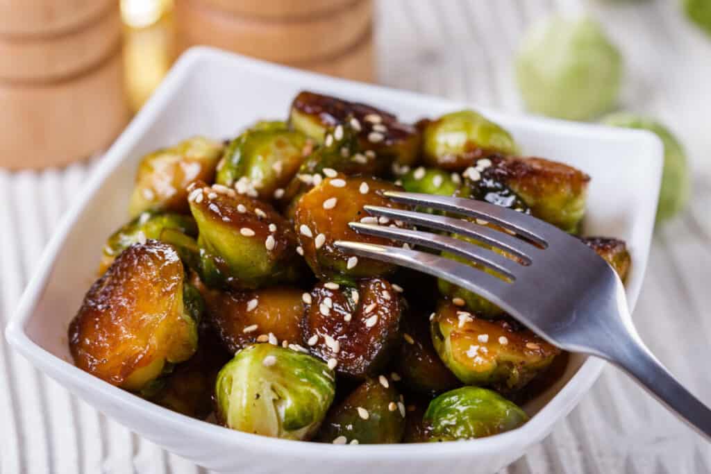 Glazed Brussel sprouts with sesame seeds in a white square bowl