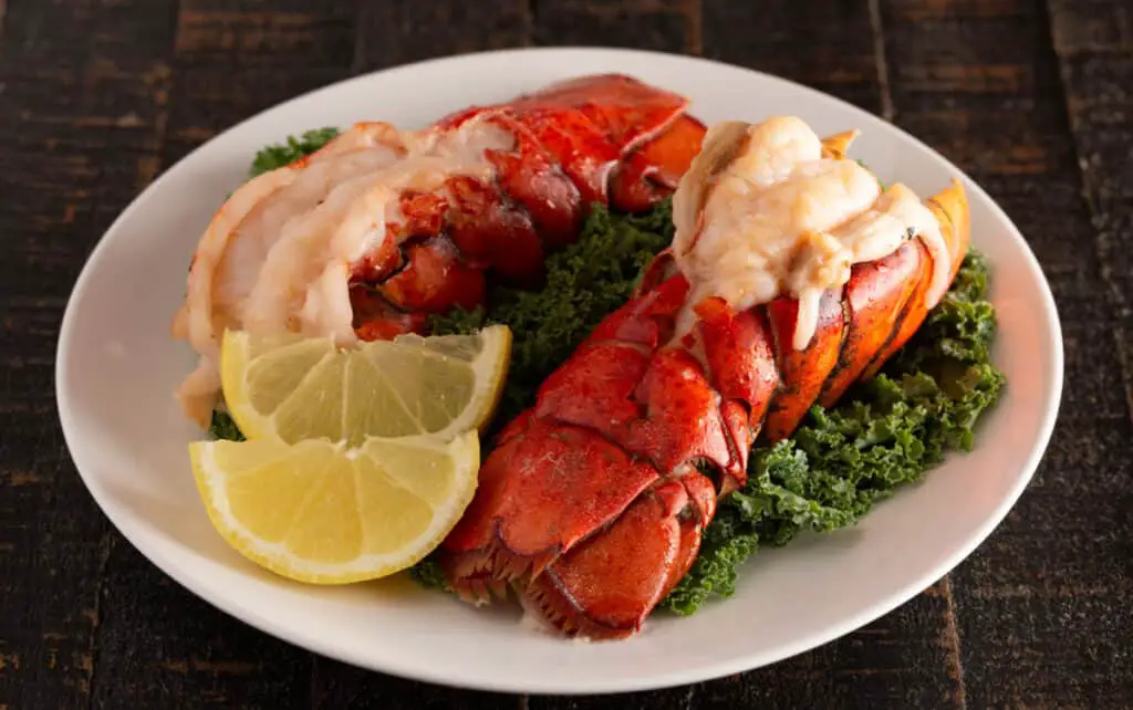 Two broiled Lobster tails on a bed of Kale