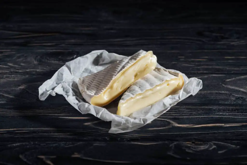 Pieces of yummy brie cheese on napkin on wooden table