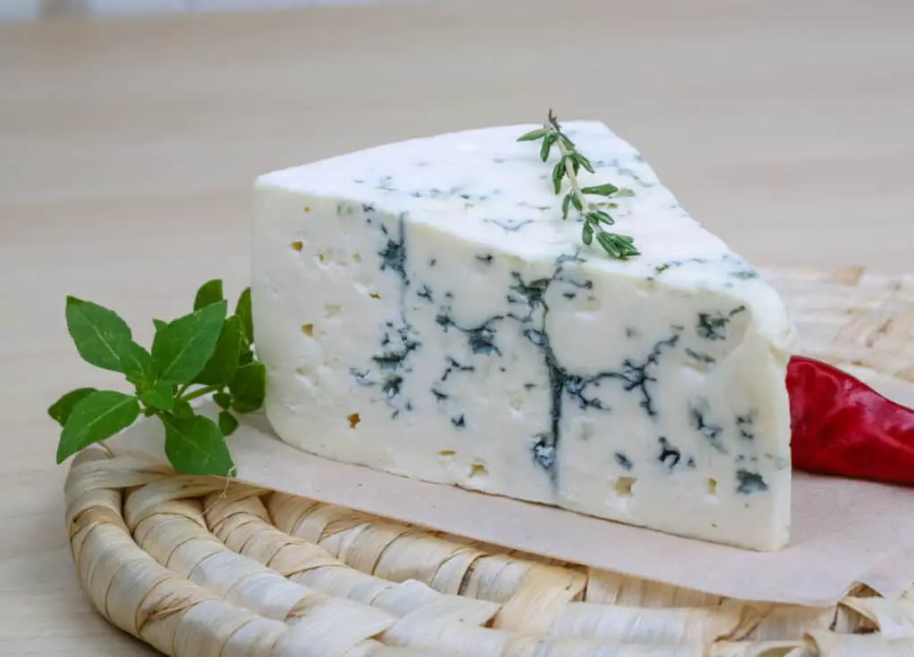 Blue cheese with basil leaves on whicker