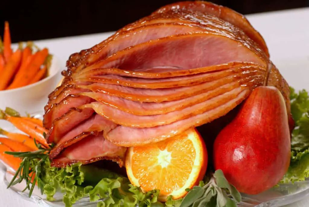 A spiral-cut honey-glazed Easter ham with fruit and carrots.