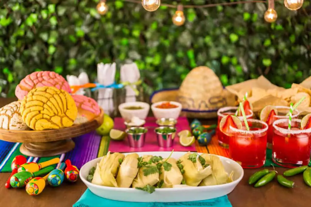 Party table with tamales, strawberry margaritas, and pan dulche bread.