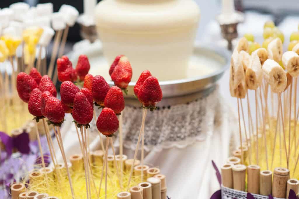 White chocolate fountain with strawberries and bananas on skewers