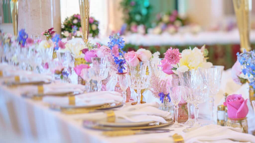 Beautiful wedding table with flowers, white table cloths, silverware, napkins and glassware