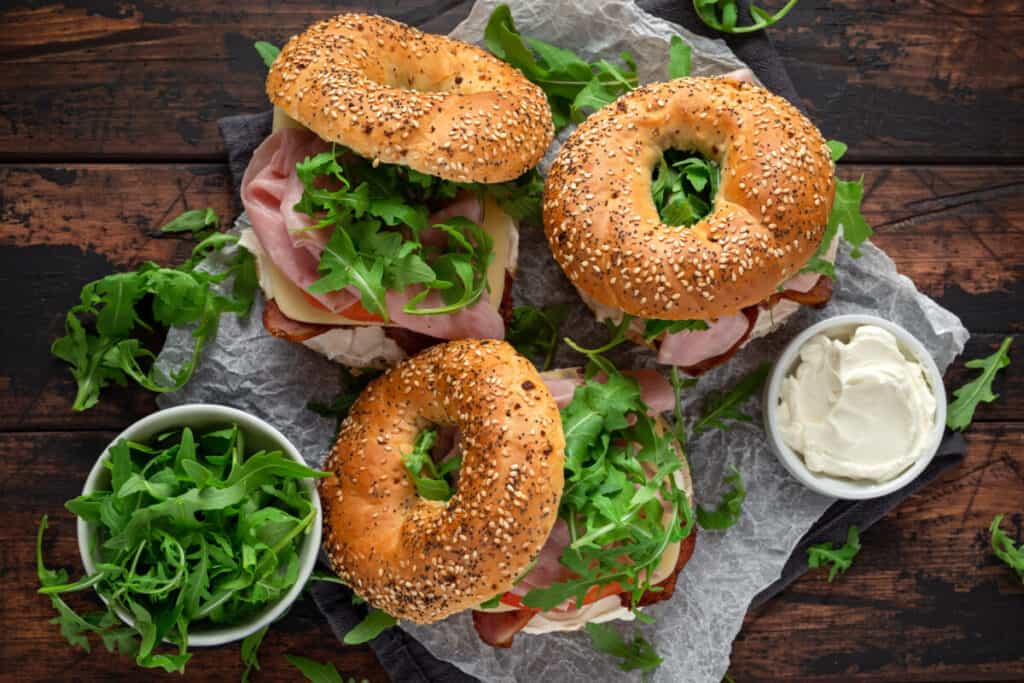 Delicious sandwich bagel with bacon and cream cheese on rustic wooden table