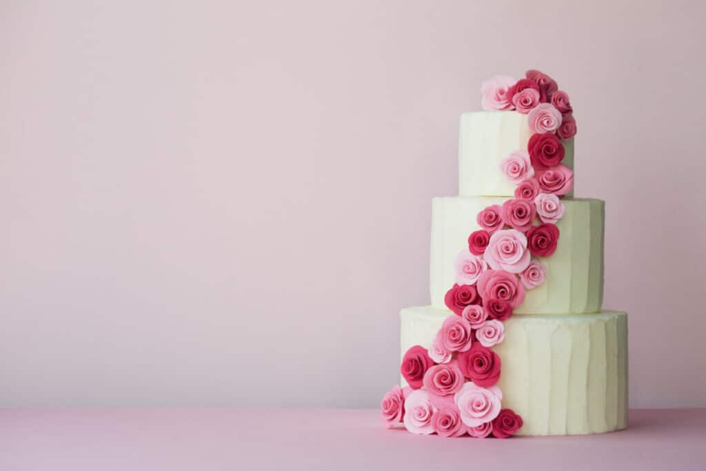 Picture of three tiered white wedding cake with pink roses