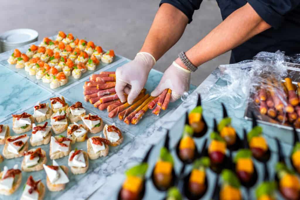A waiter in gloves at a banquet prepares a table of appetizers for guests