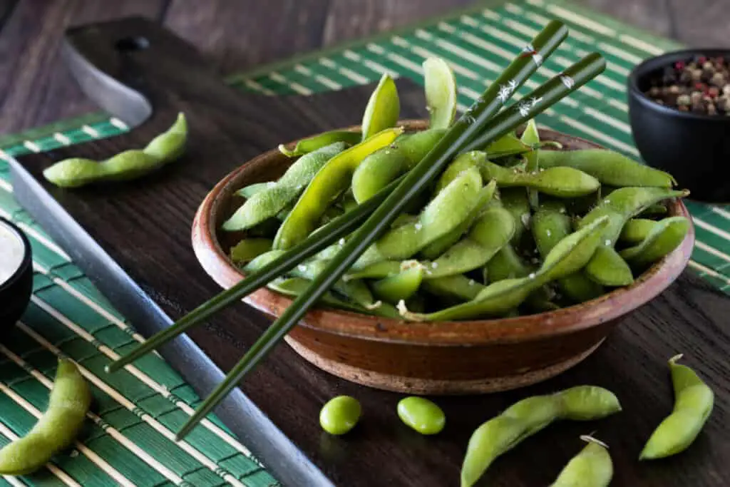 Boiled edamame beans in a wooden bowl on a rustic wooden table
