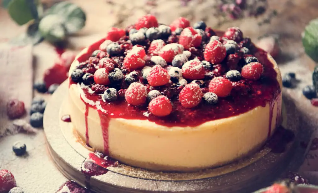 Cheesecake with raspberries and blueberries on a wooden round