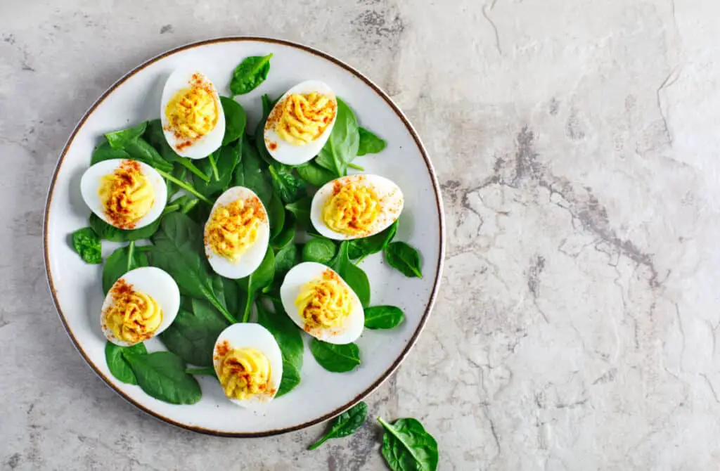 Deviled eggs with paprika with spinach on a white plate