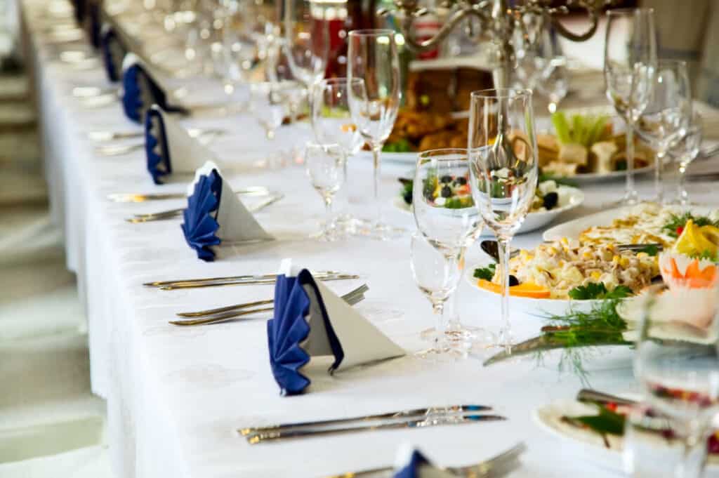 Fancy wedding table set with blued fanned napkins, glassware, and food