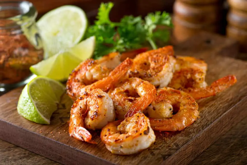 Fresh steamed shrimp creole with lime on a plank background
