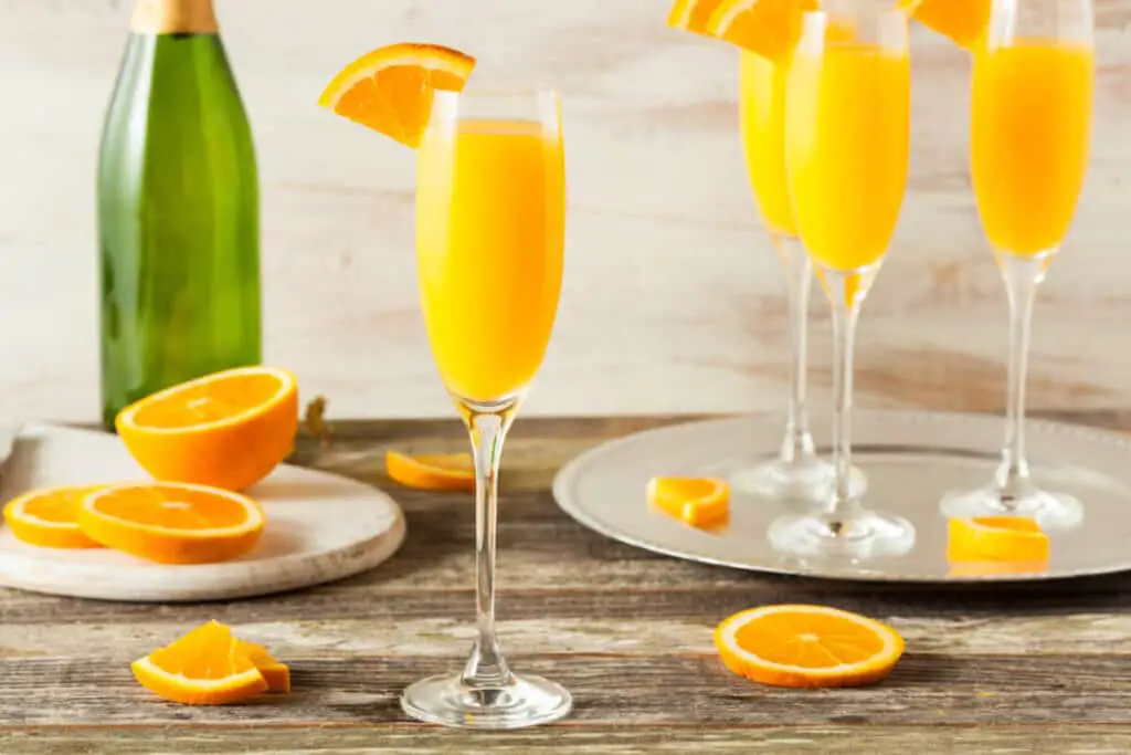 Glasses of mimosas with orange slices on a wooden table