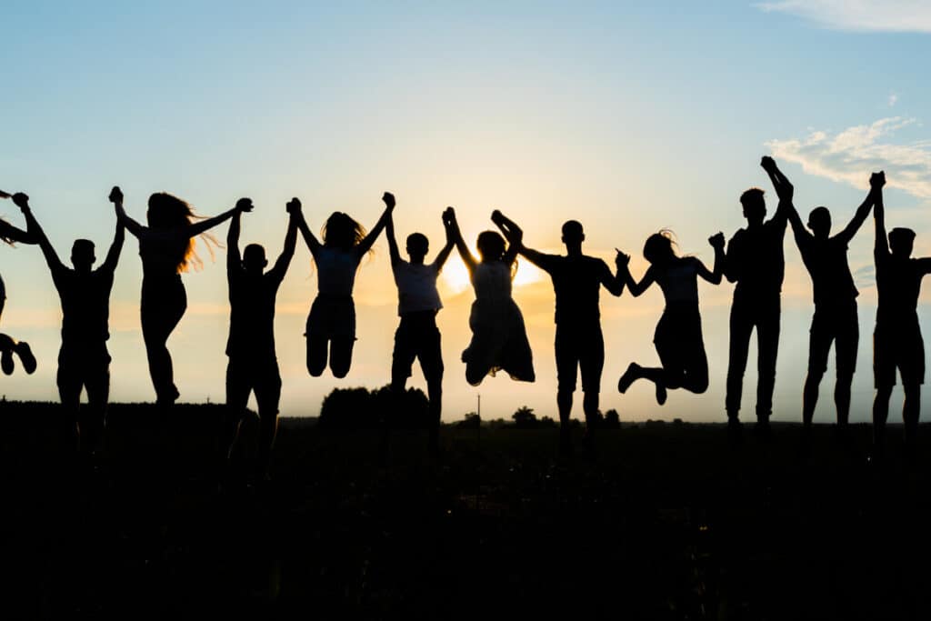 Silhouettes of jumping friends on a sunset background