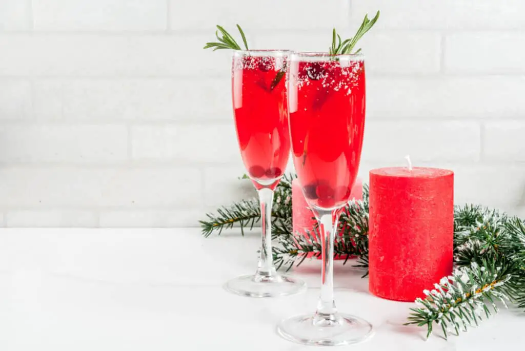 Christmas cranberry mimosas with rosemary on a white marble countertop