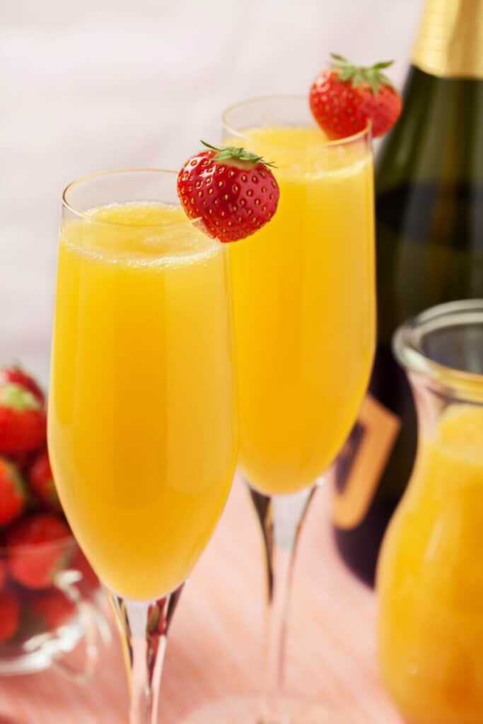 Two glasses of mimosas (champagne with orange juice) and fresh strawberries