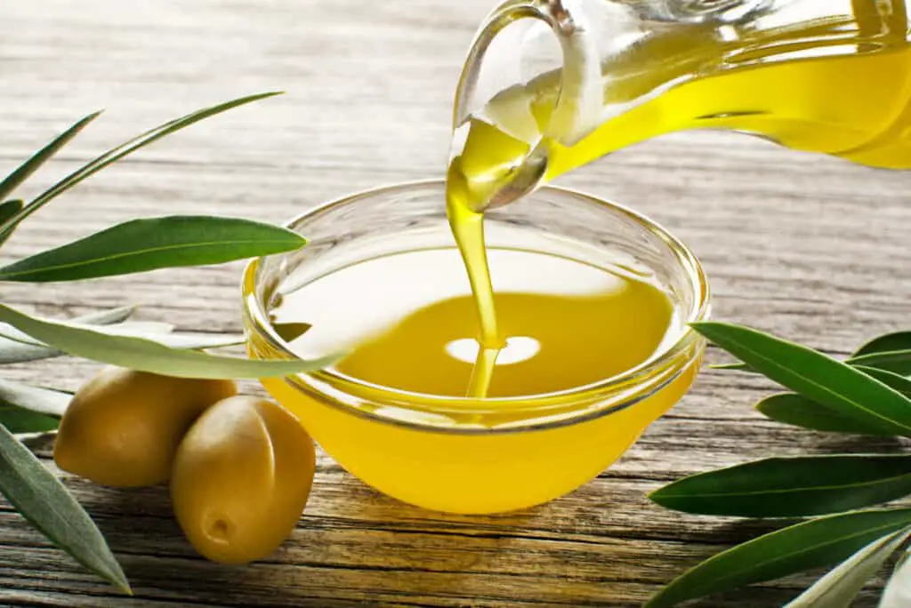 Bottle pouring virgin olive oil in a bowl close up