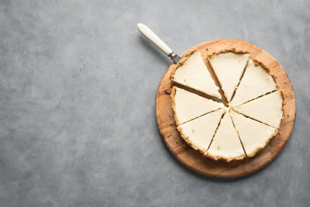 Plain cheesecake sliced up on a wooden round