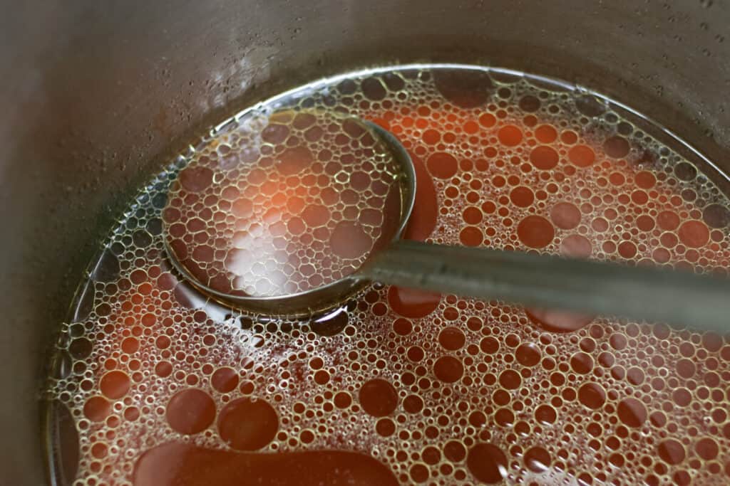 Simmering beef stock in a pot with a ladle