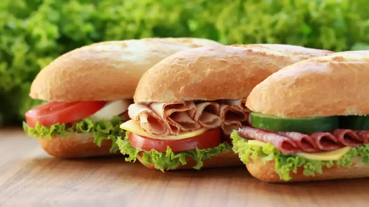 Sub sandwiches with meat, cheese, lettuce, tomato, and cucumber