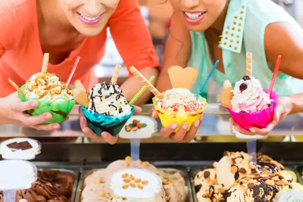 Two women with bowls of various flavors of ice cream and toppings
