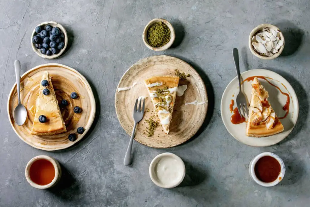 Variety of cheesecakes on plate with blueberry, pistachio, and caramel toppings