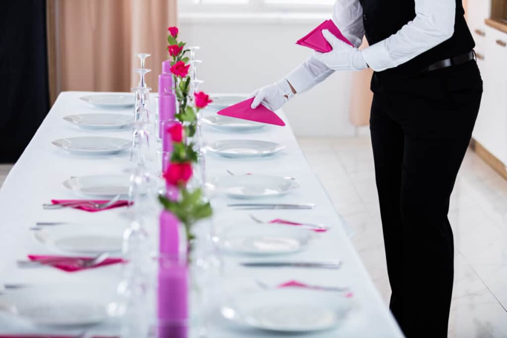 White table set with white plates, pink napkins, and pink flowers