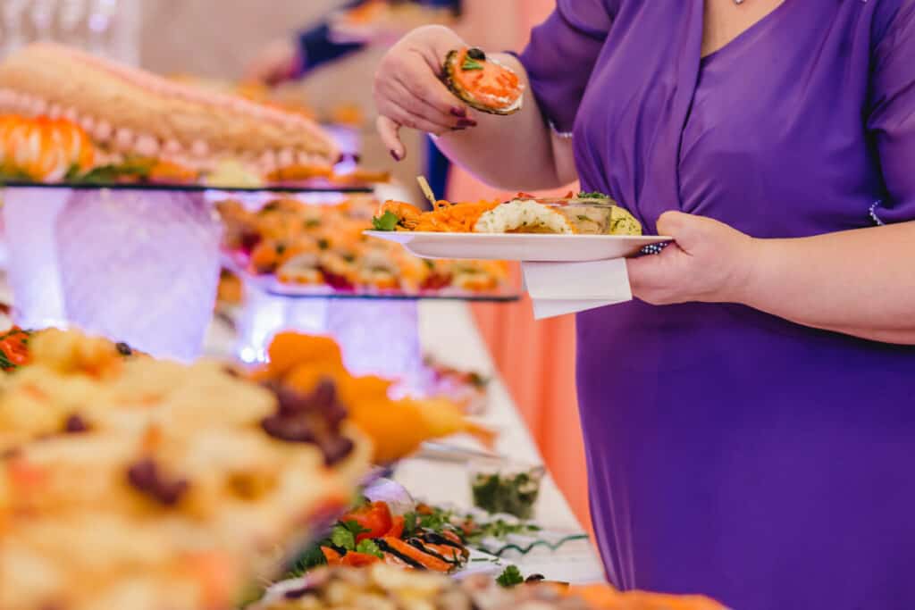 Woman in purple dress getting a plate of food at wedding