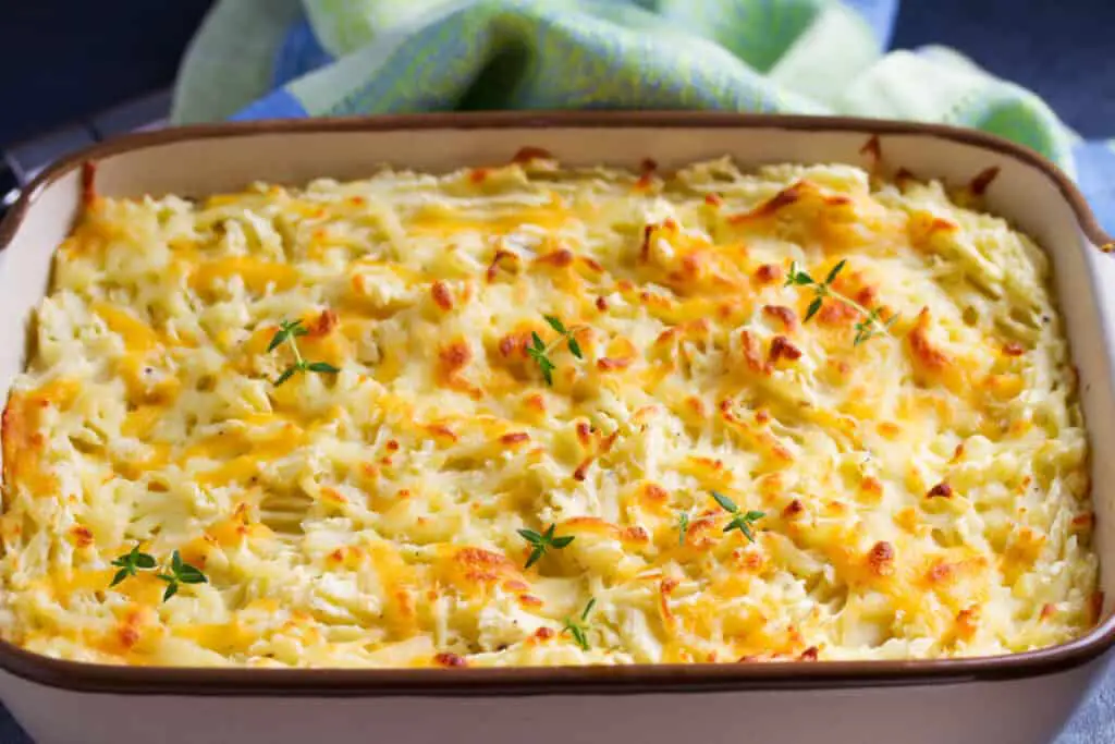 Funeral potatoes in a white and brown casserole dish