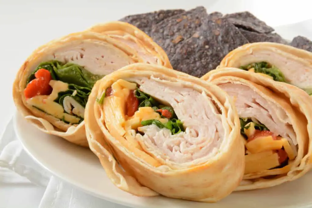 Pinwheel sandwiches with turkey, cheese, spinach, and tomato