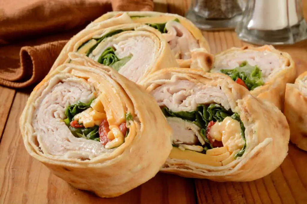 Pinwheel sandwiches with turkey, cheese, spinach, and tomato