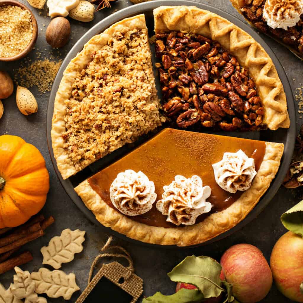 Pumpkin, apple crumble, and pecan pie with Thanksgiving decorations