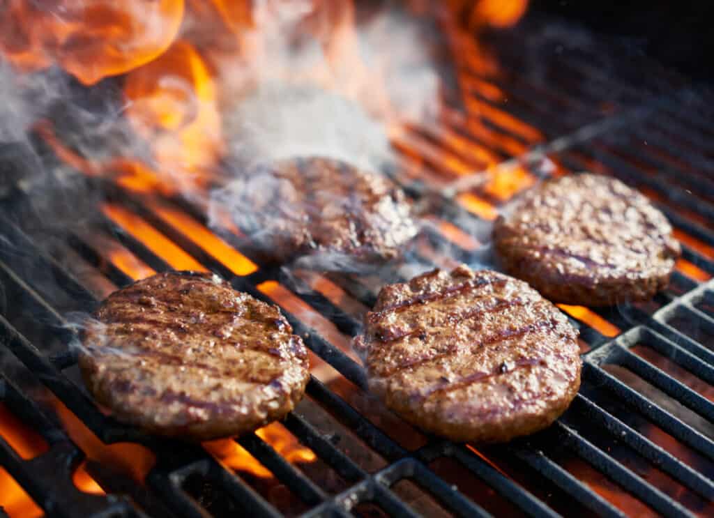 Cooking burgers on a hot grill with flames