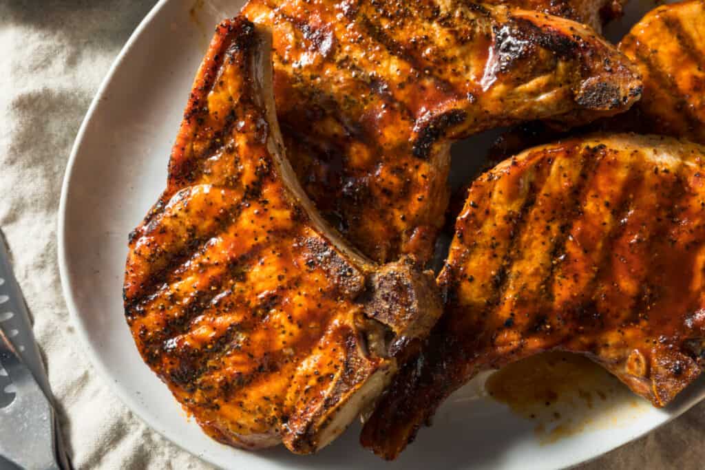 Grilled and glazed pork chops on a white plate