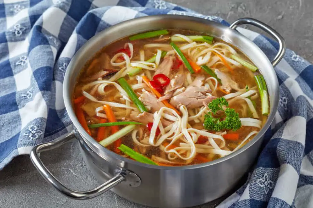 Poultry noodle vegetables soup in a metal casserole