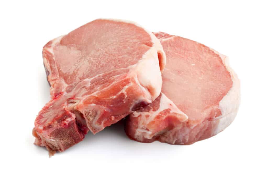 Two raw pork chops on white background