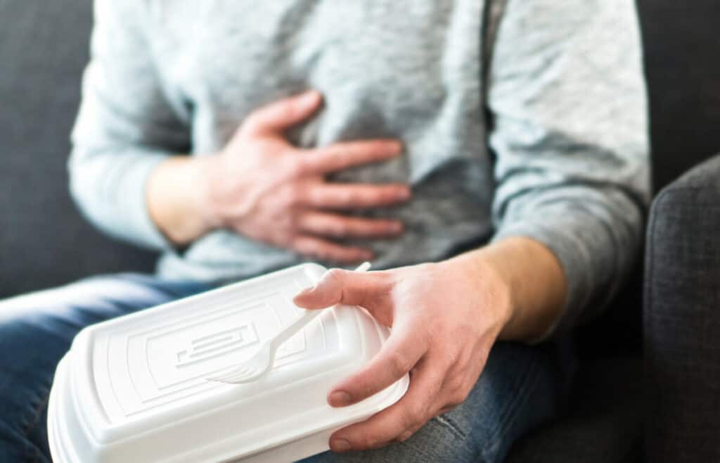 Man holding a to go container having stomach pain