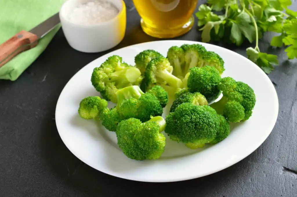 Broccoli on white plate on a dark surface