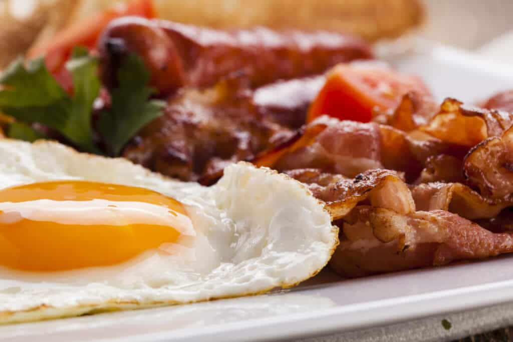 English breakfast with bacon, sausage, fried egg, baked beans and tea or orange juice