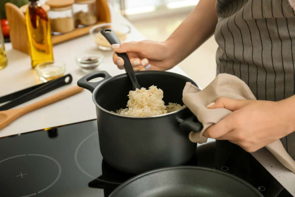 Woman cooking rice on stove in kitchen