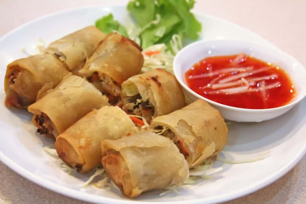 Fried dumpling being dipped in soy sauce with chop sticks