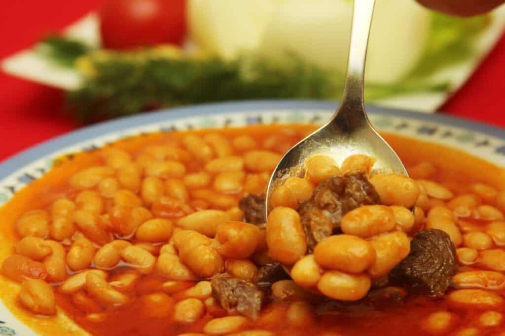 Baked beans with stew meat in a white and blue bowl